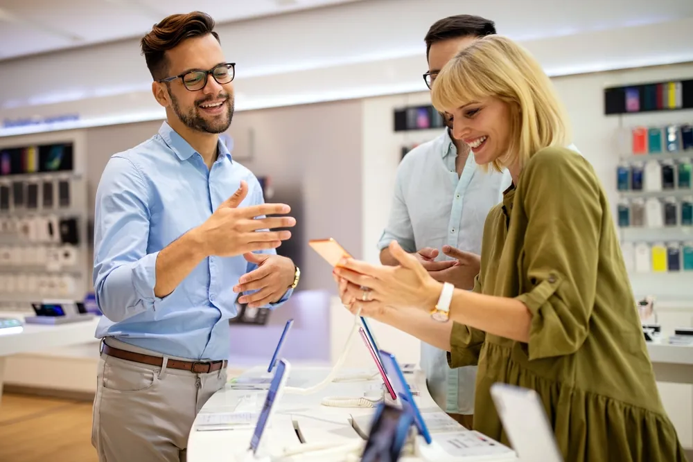 A sales assistant explaining the features of a new phone to interested customers